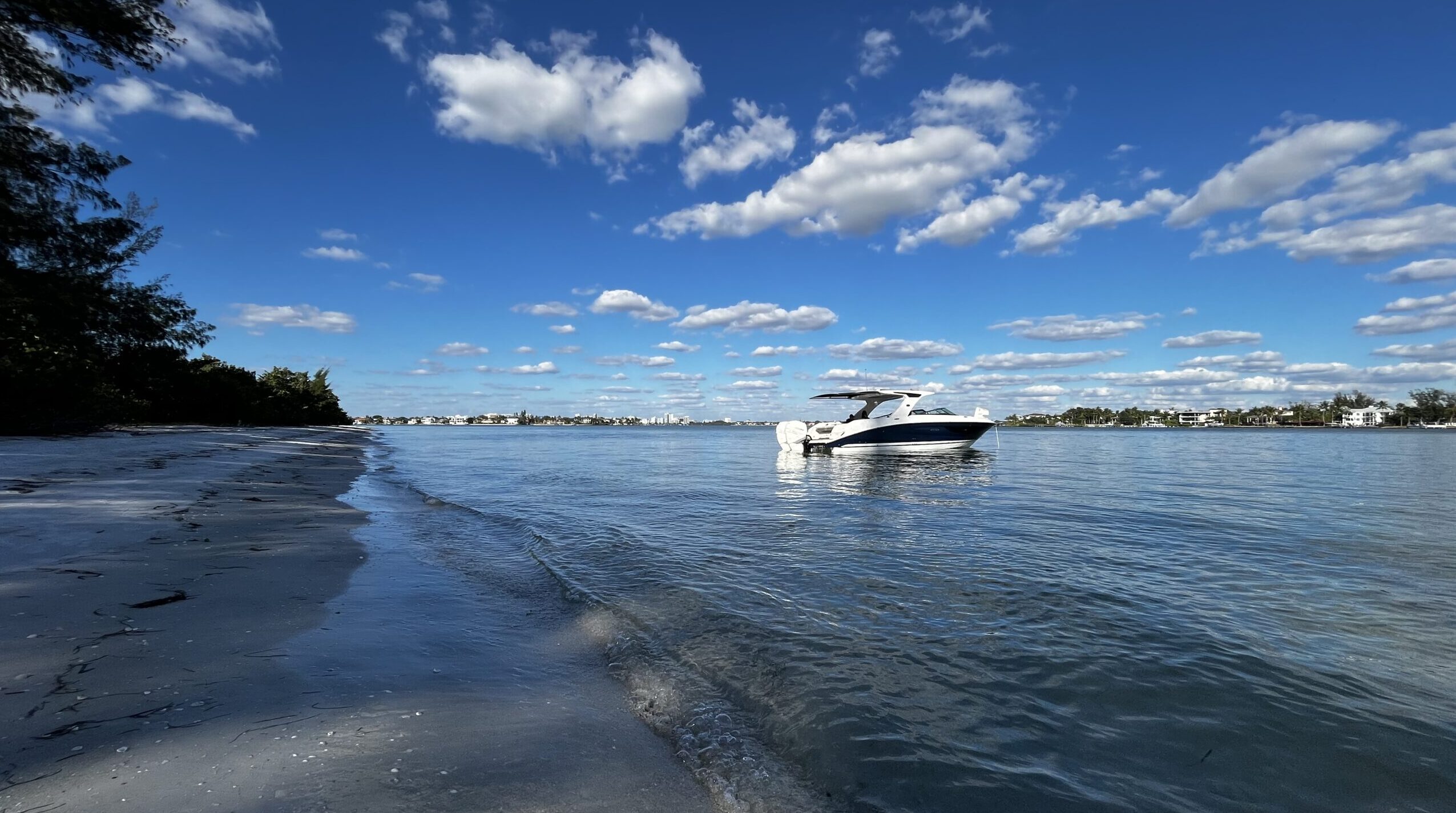 boat anchored just off shore of a beach with calm waters